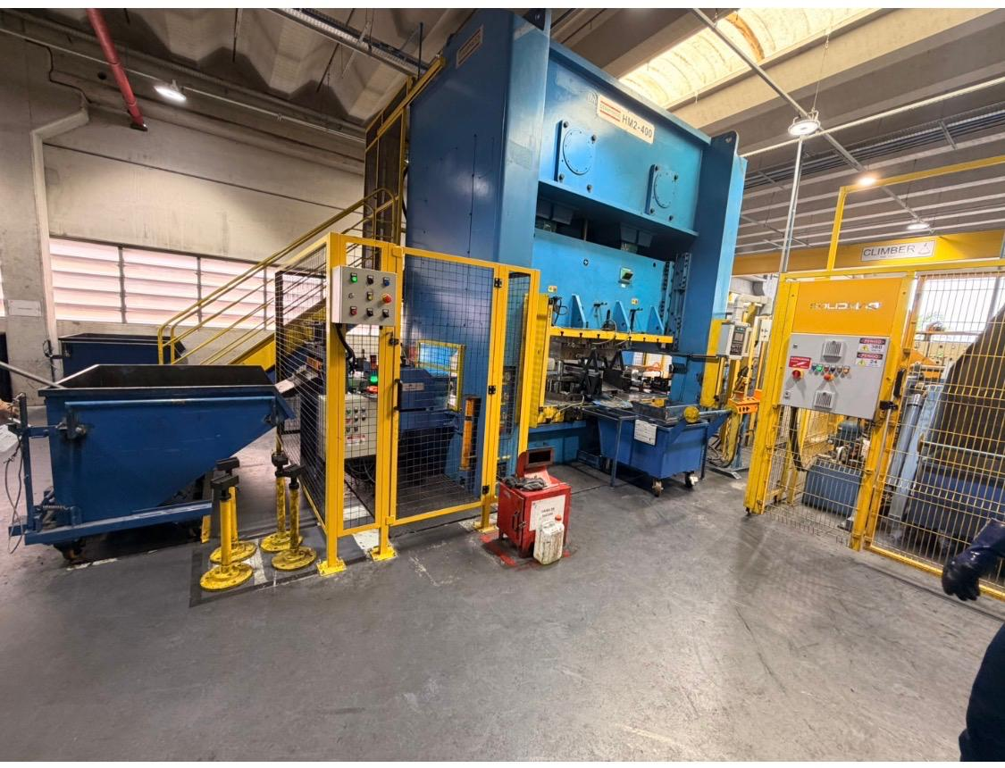 Prensa Stampress HM2-400 cercada por proteção amarela em planta industrial integrada